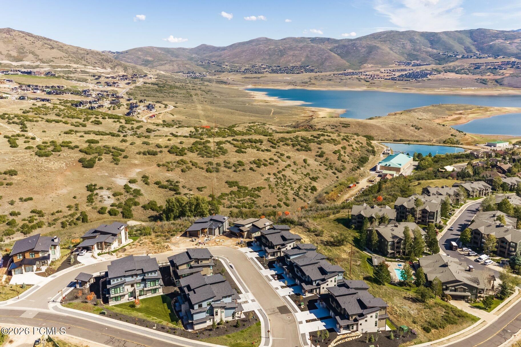 Aerial view of a residential community beside a reservoir, with surrounding hills and mountain ridges.
