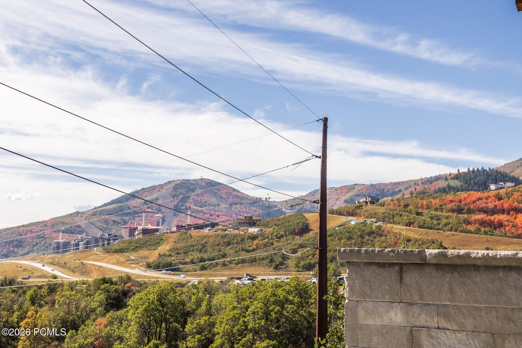 Mountain valley with autumn foliage, scattered buildings, and utility lines in the foreground.