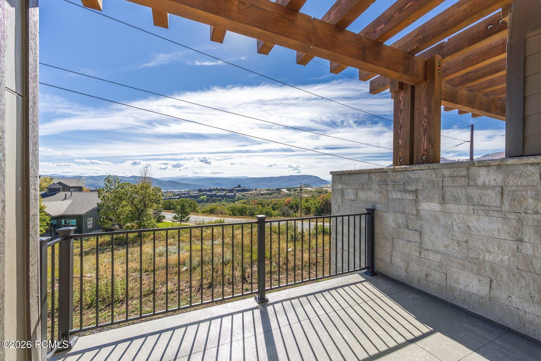 Covered balcony with a timber pergola overlooking autumn foliage and distant mountain ridges.