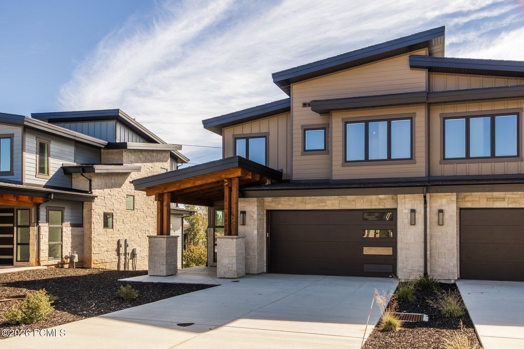 Modern two-story home with stone facade, covered entry, and wide driveway.