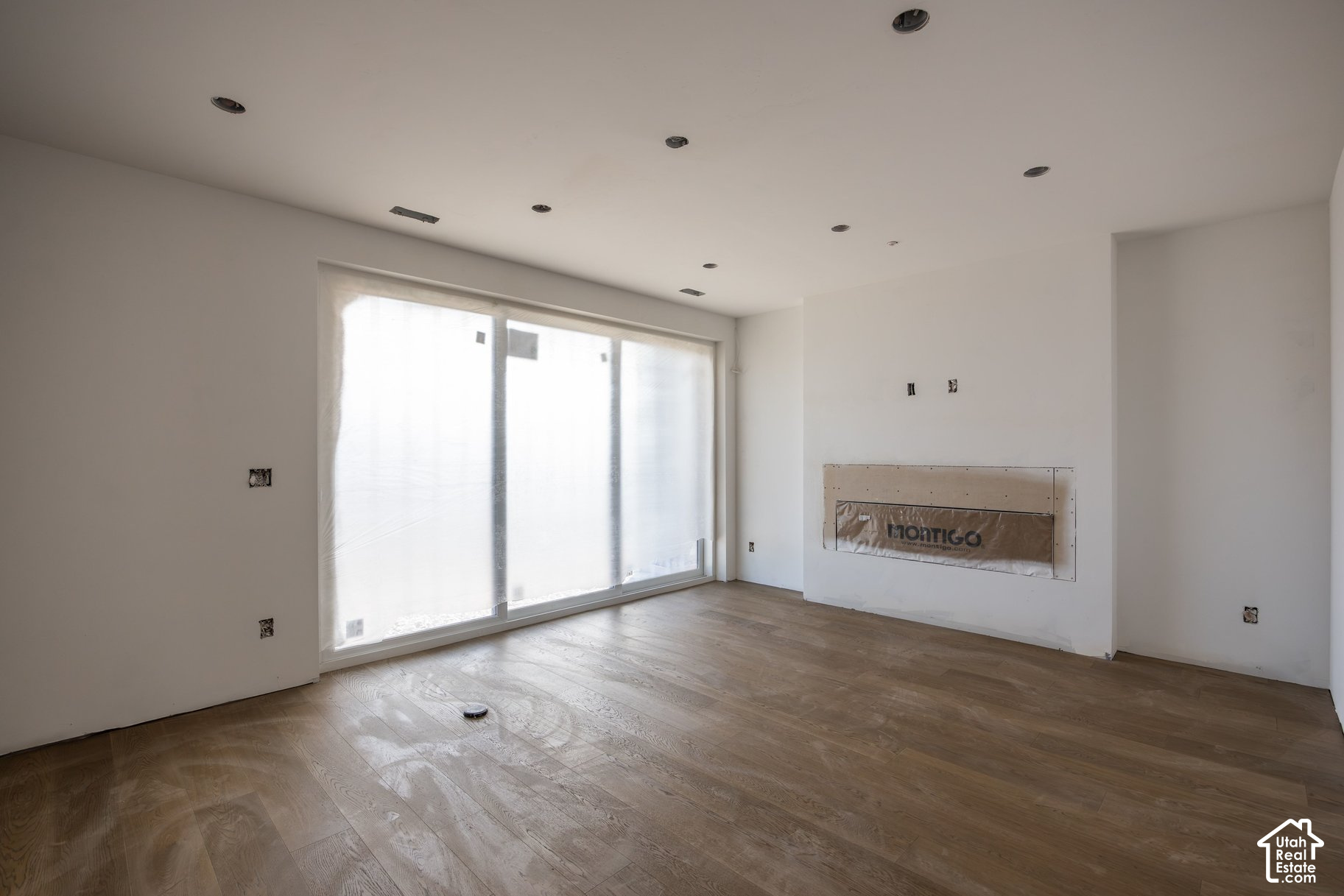 Unfinished living room with wide covered sliding glass doors and an incomplete fireplace.