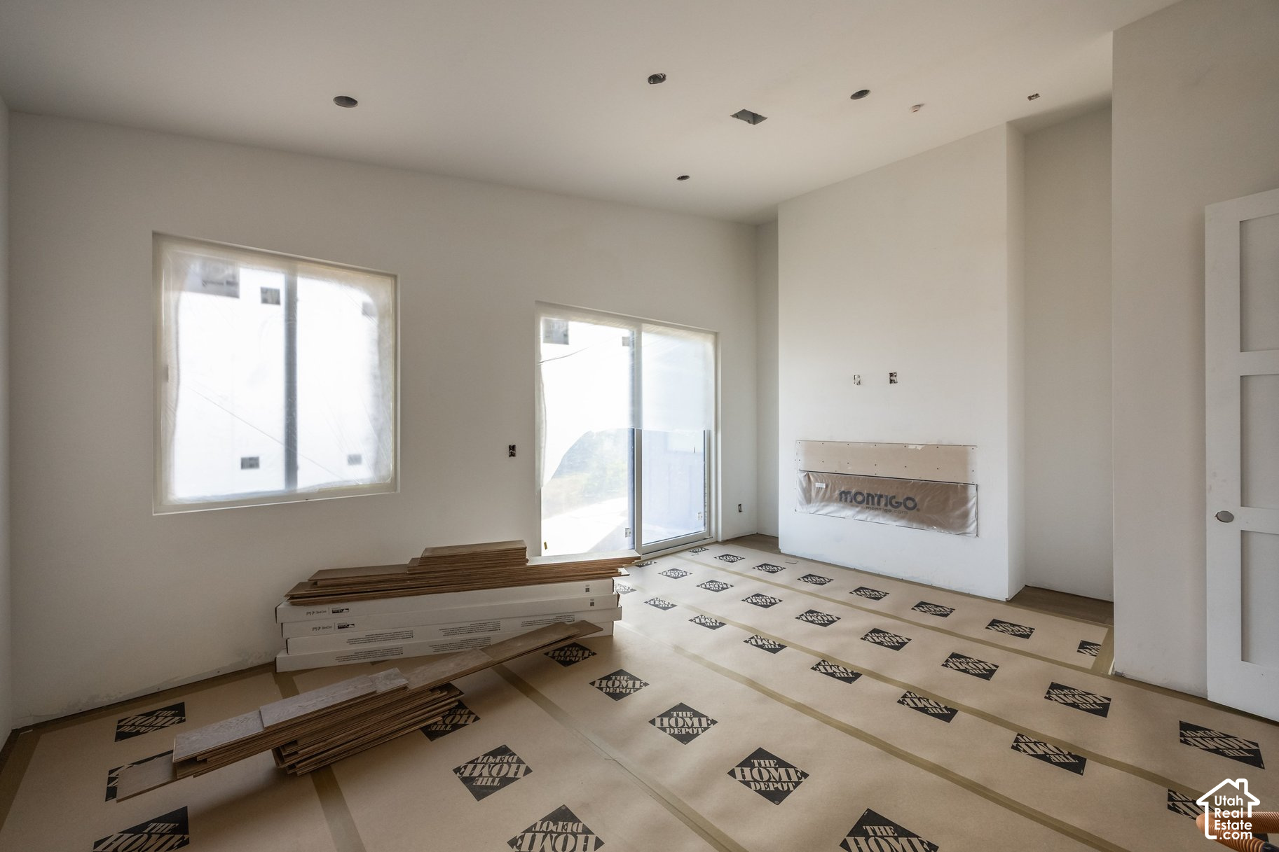 Unfinished living room with a Montigo fireplace, large windows, and flooring materials stacked on the floor.