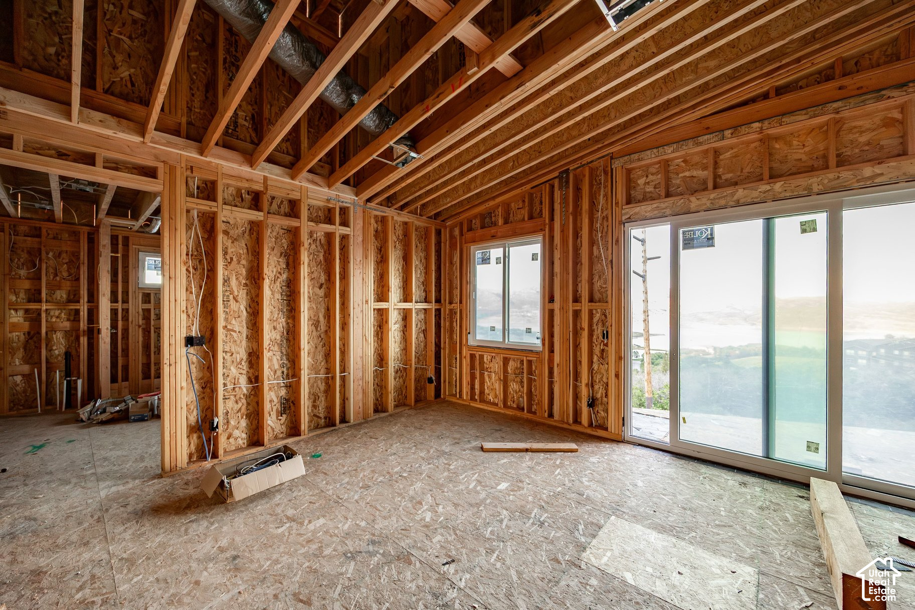 Unfinished framed room with sliding glass doors overlooking water and hills.