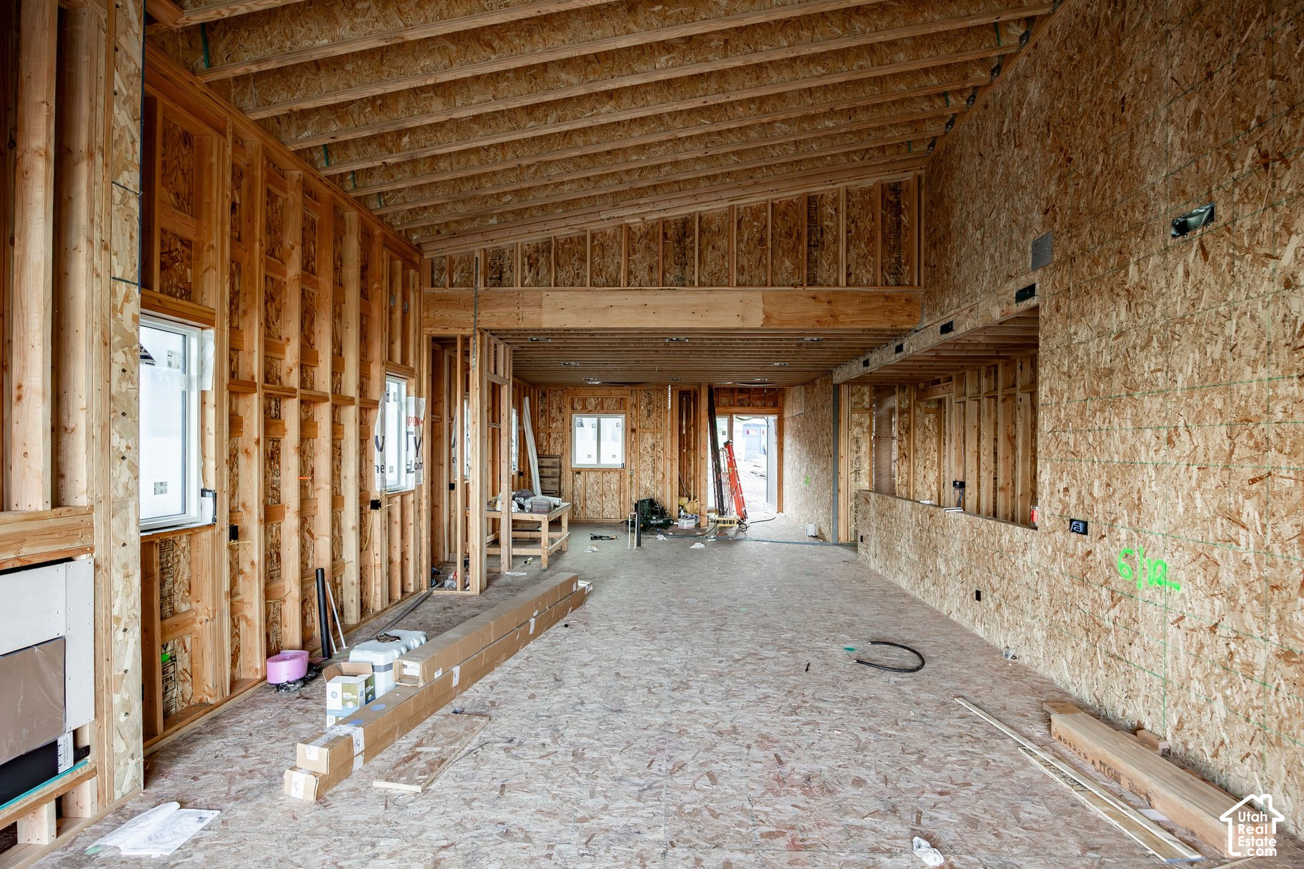 Unfinished home interior with exposed framing, ceiling joists, and windows.