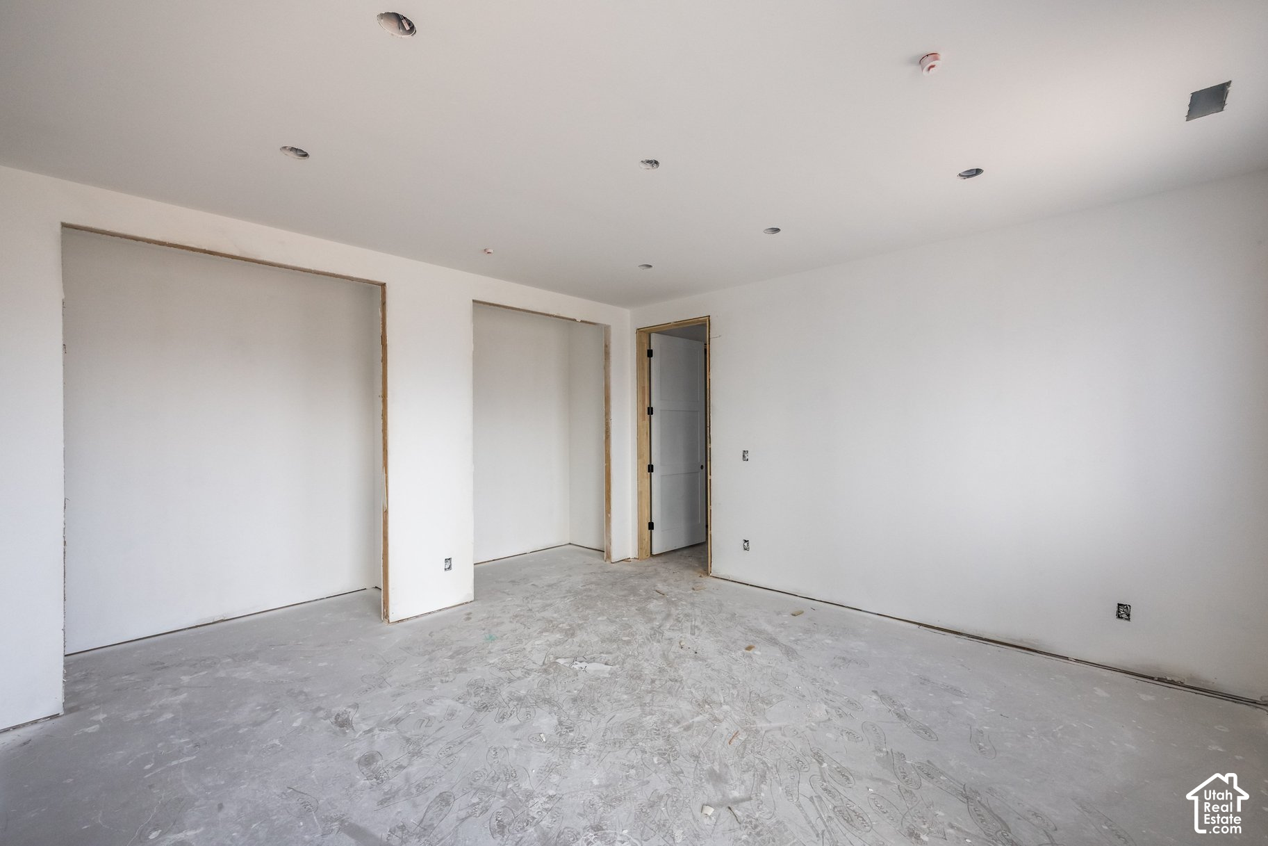 Unfinished room with a bare concrete floor, recessed lights, and untrimmed doorways.