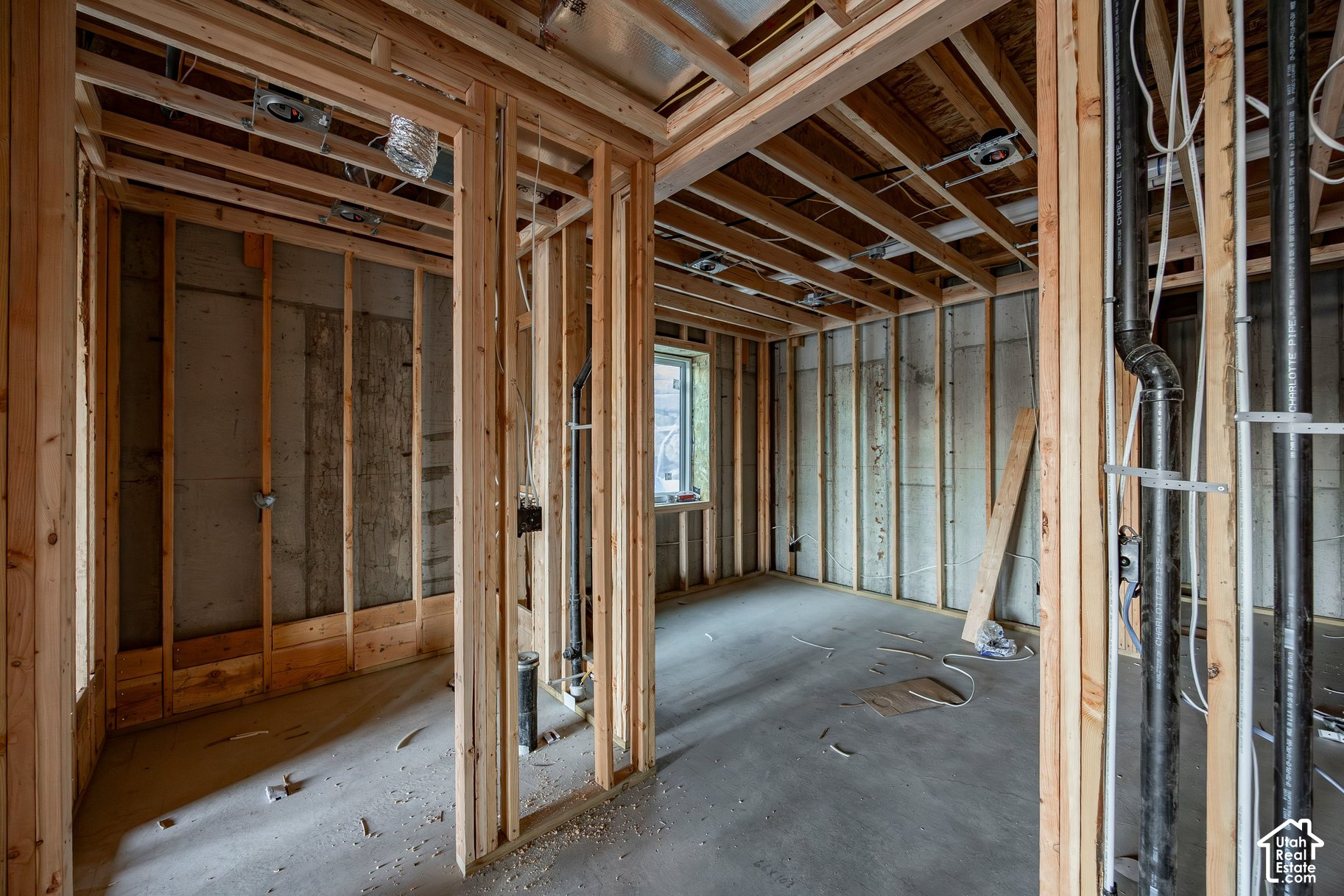 Unfinished interior with exposed wood framing, concrete foundation walls, and visible plumbing and electrical lines.