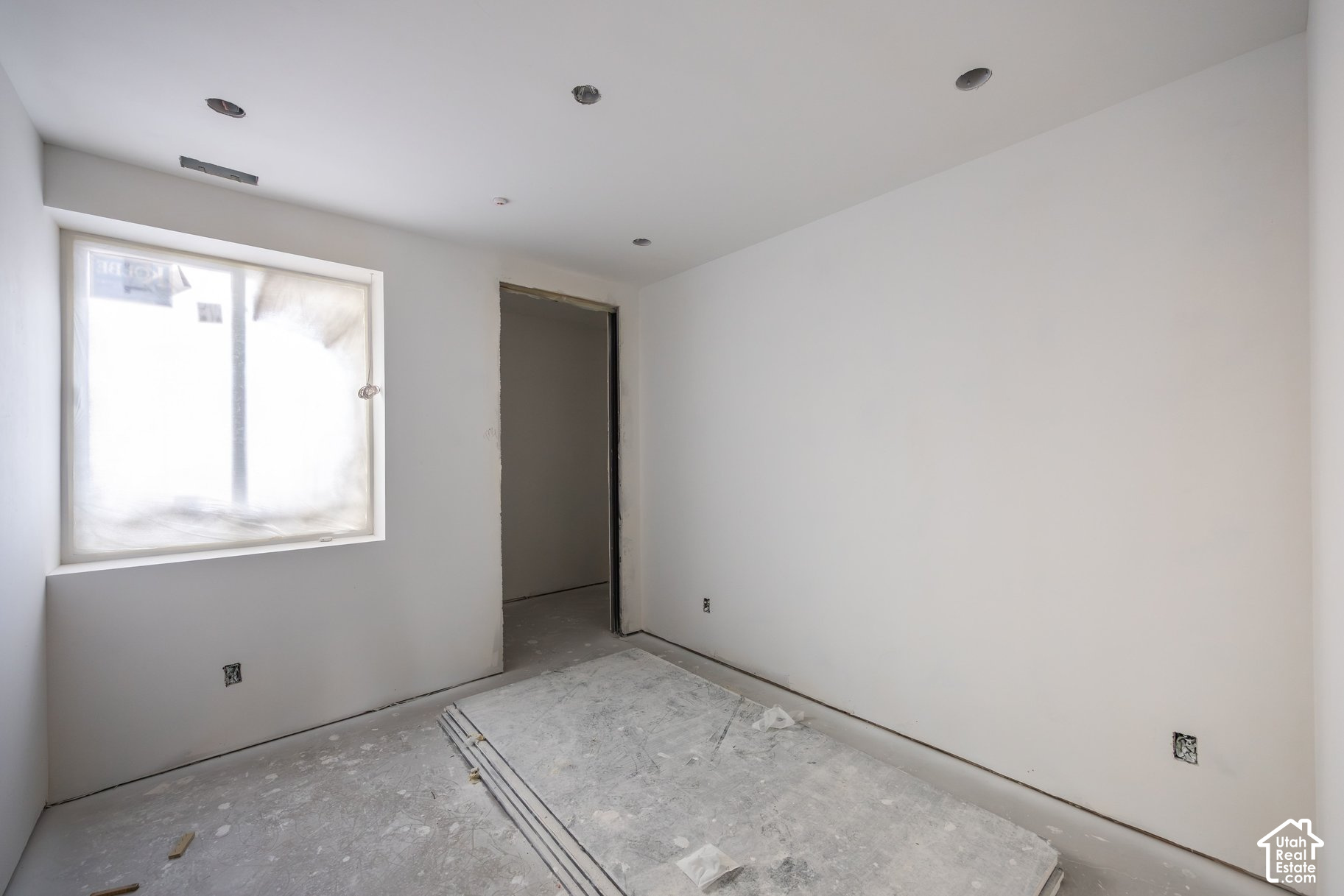 Unfinished room with a large window, recessed lights, and a dusty construction floor.