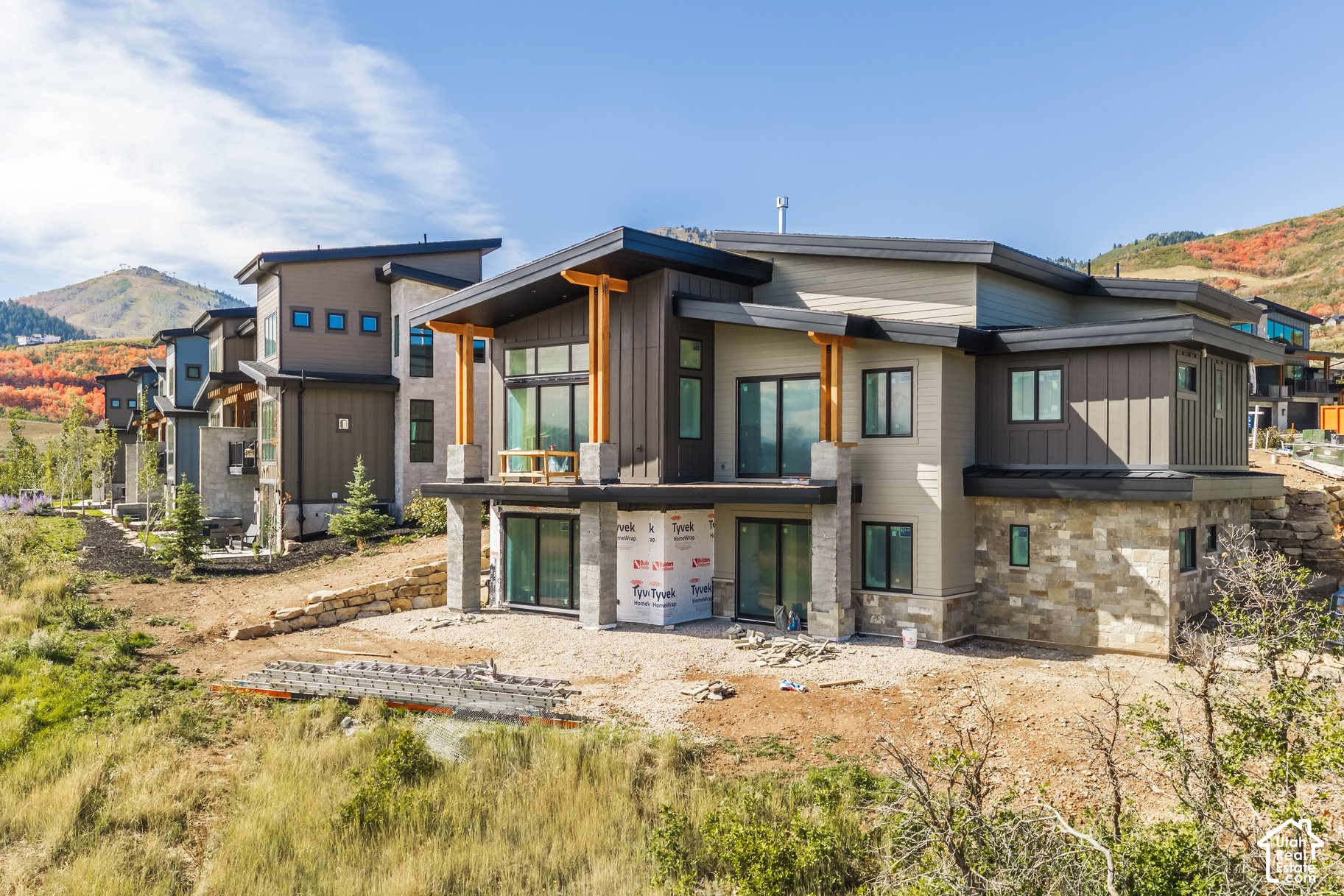 Modern mountain home under construction with a stone lower facade and covered timber porch.