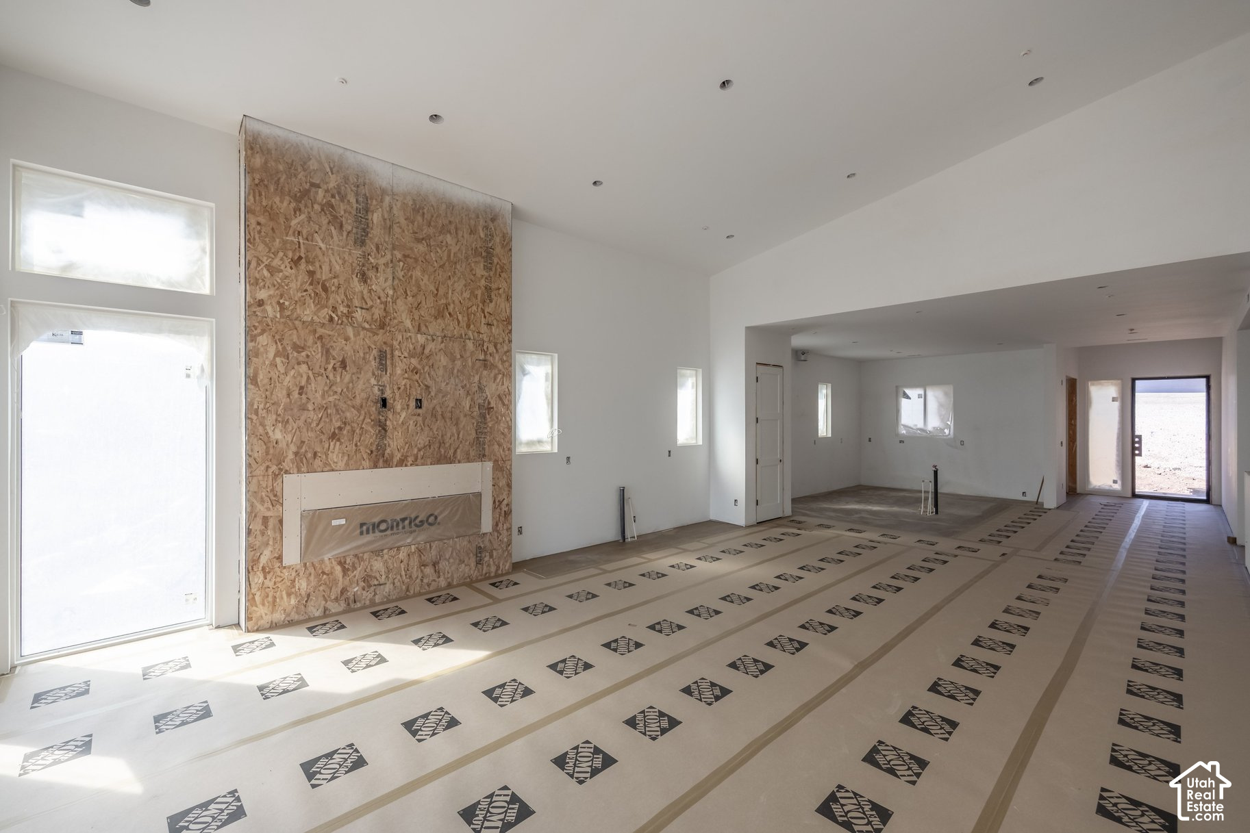Unfinished living area with a plywood fireplace wall and protective floor covering.