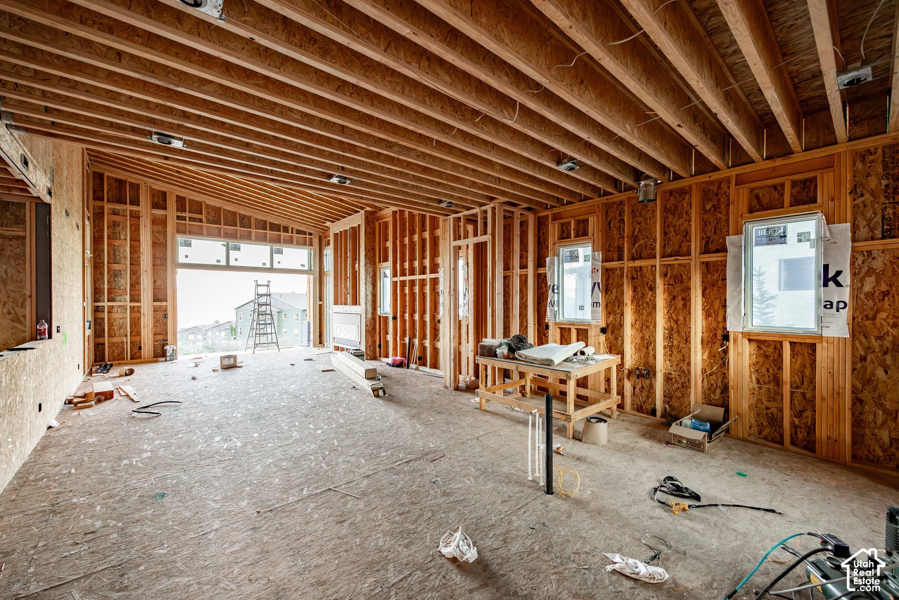 Unfinished open room with exposed timber framing, roof trusses, and windows.