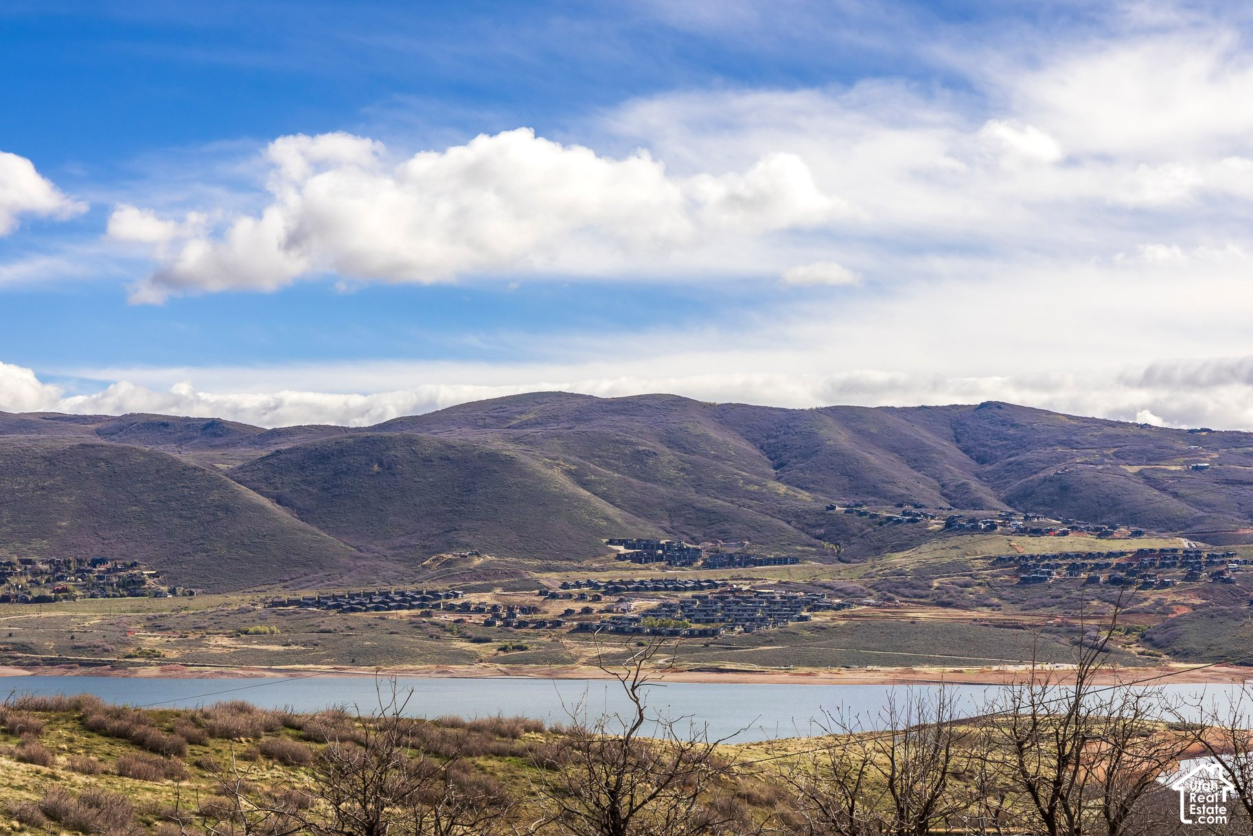 Lake and valley neighborhood beneath rolling hills, viewed from a hillside.