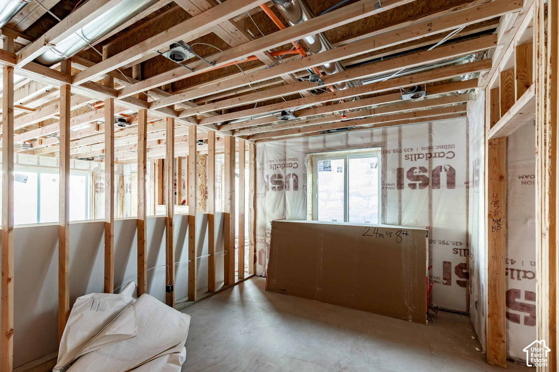 Unfinished room with exposed wood framing, overhead ductwork and construction materials.