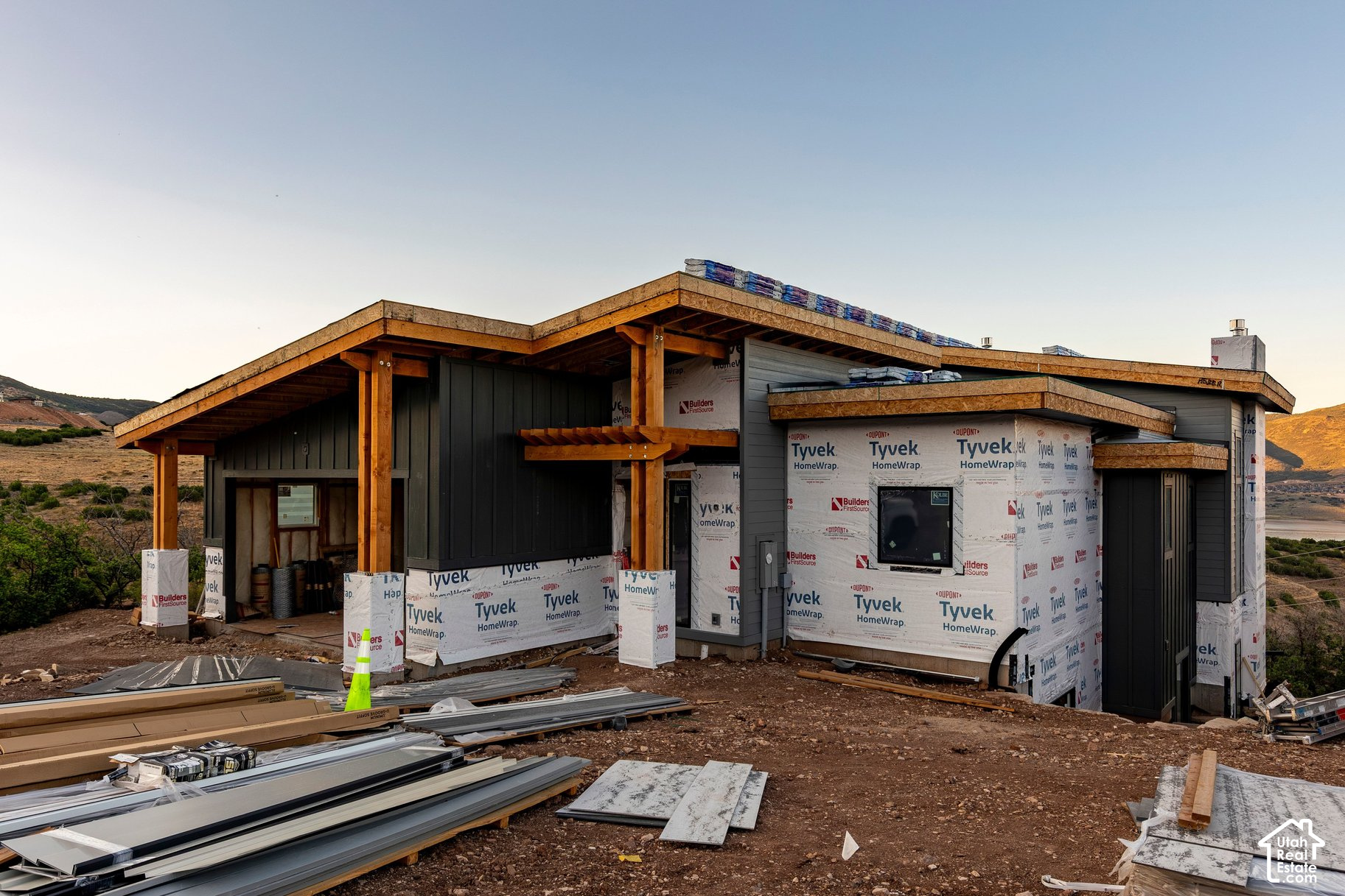 Modern home under construction with exposed timber eaves and Tyvek-wrapped exterior.