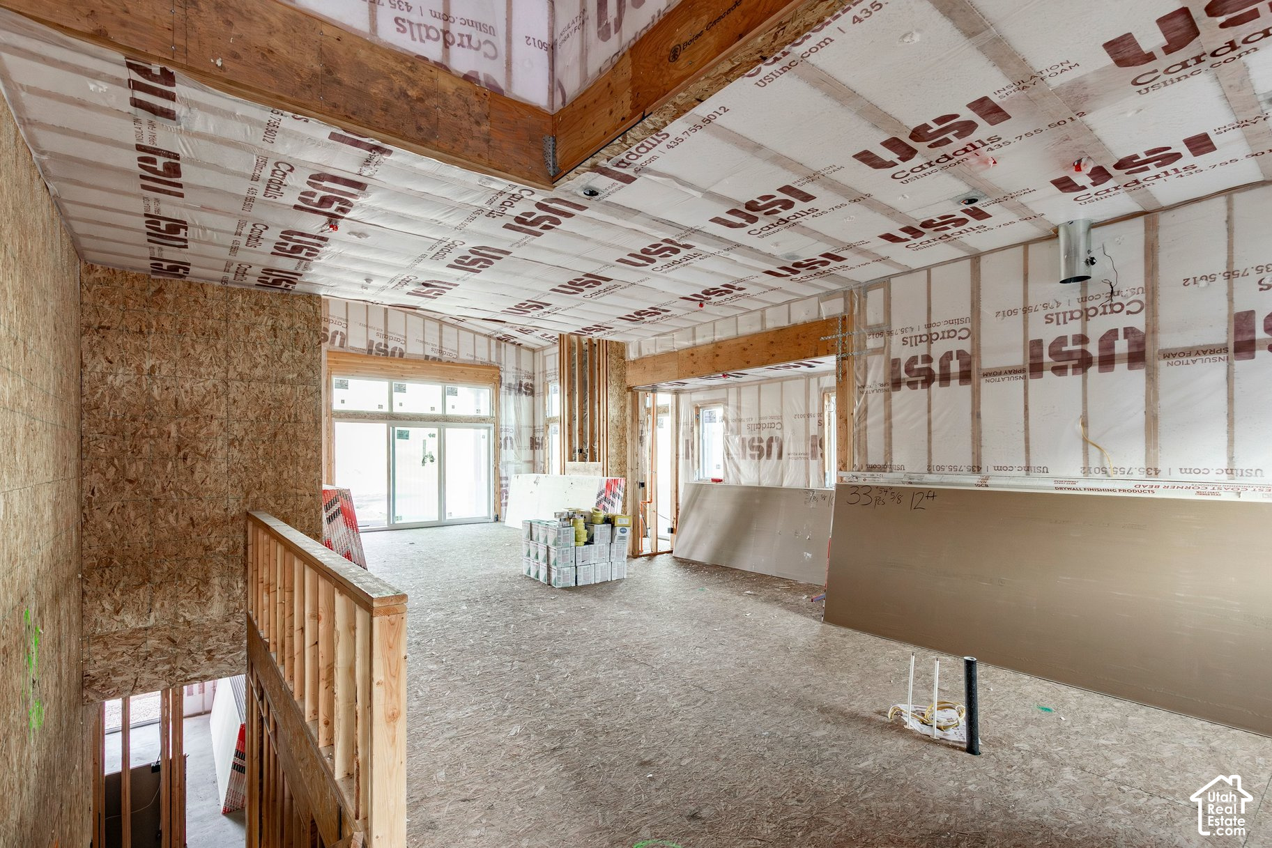 Unfinished home interior with exposed framing, ceiling insulation, and large windows.