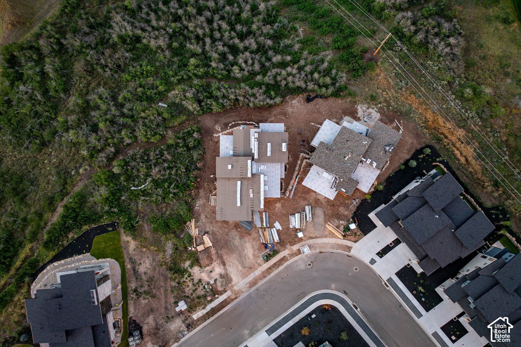 Home under construction on a wooded lot beside a cul-de-sac, viewed from above.