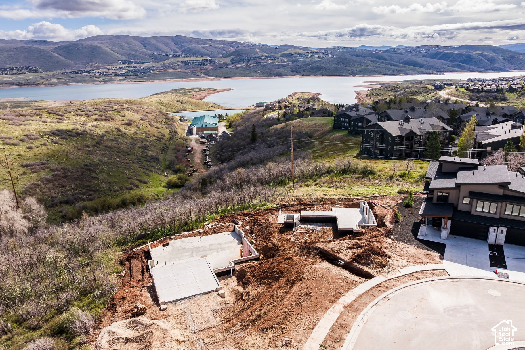 Hillside construction lot with concrete foundations overlooking a reservoir and mountain ridges.