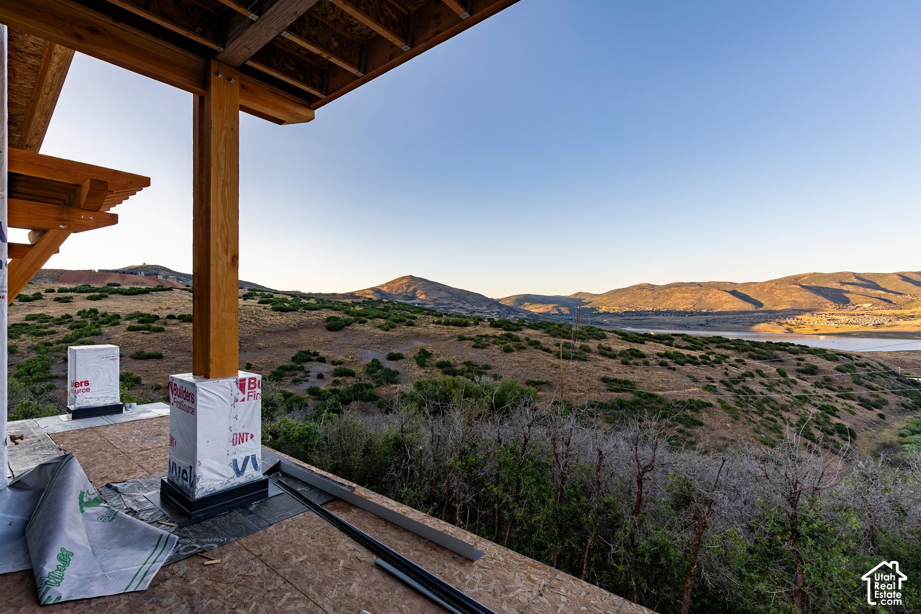 Unfinished porch overlooks a reservoir and sunlit mountain ridges.