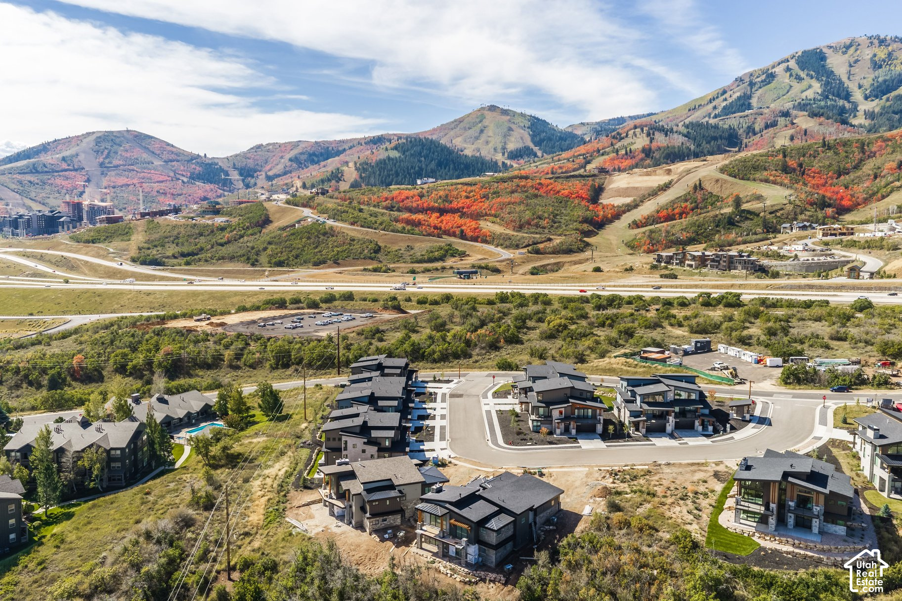 Aerial view of a residential development with modern homes and autumn-colored mountain slopes beyond.