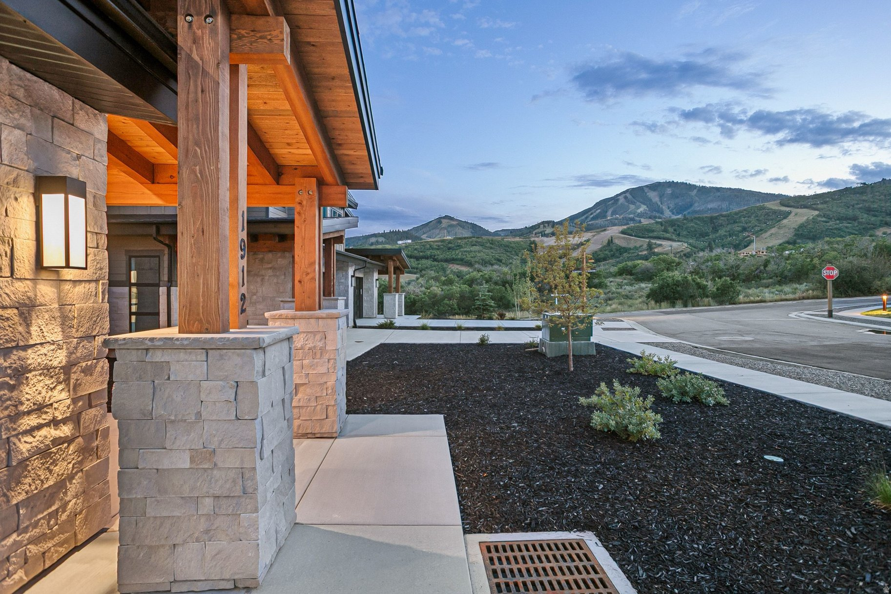Stone-and-timber home with a covered porch and mountain views at dusk.