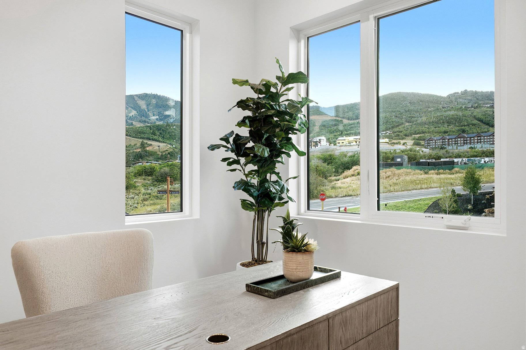 Staged office nook with a wood desk and mountain views through large windows.