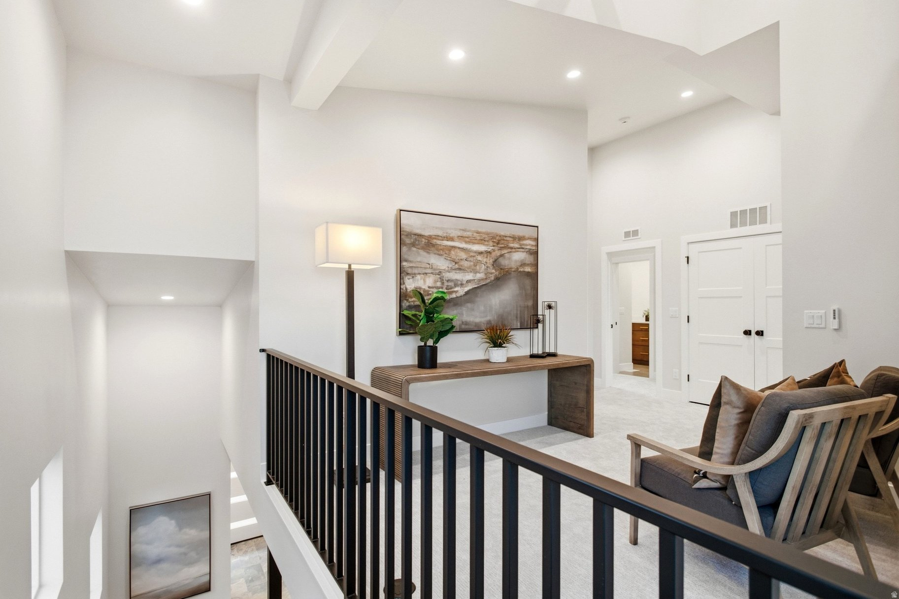 Furnished upstairs landing with a console table and cushioned chairs beside an open staircase.