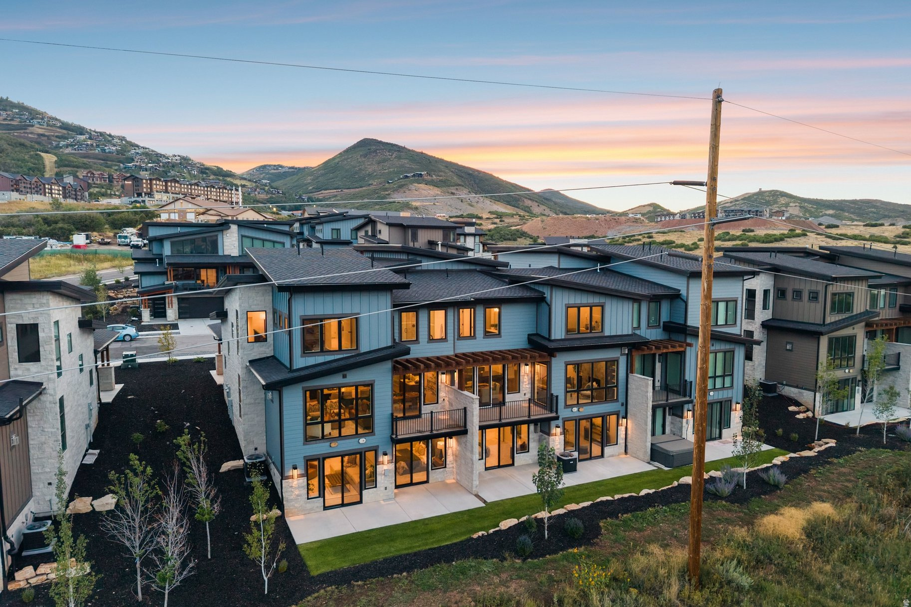 Modern hillside homes with mountain views and warm windows at dusk.