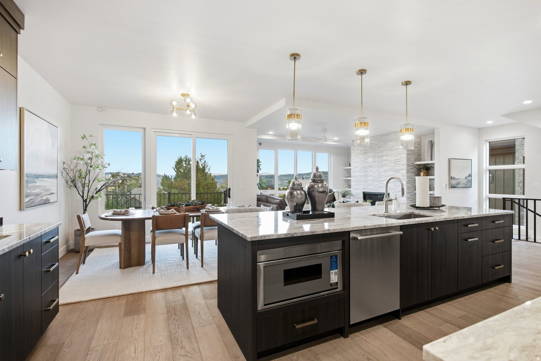 Open-plan kitchen and dining area with a marble island and mountain views through large windows.