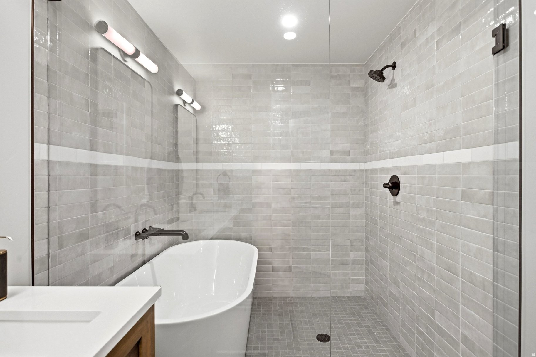 Modern bathroom with a freestanding tub and gray-tiled walk-in shower.