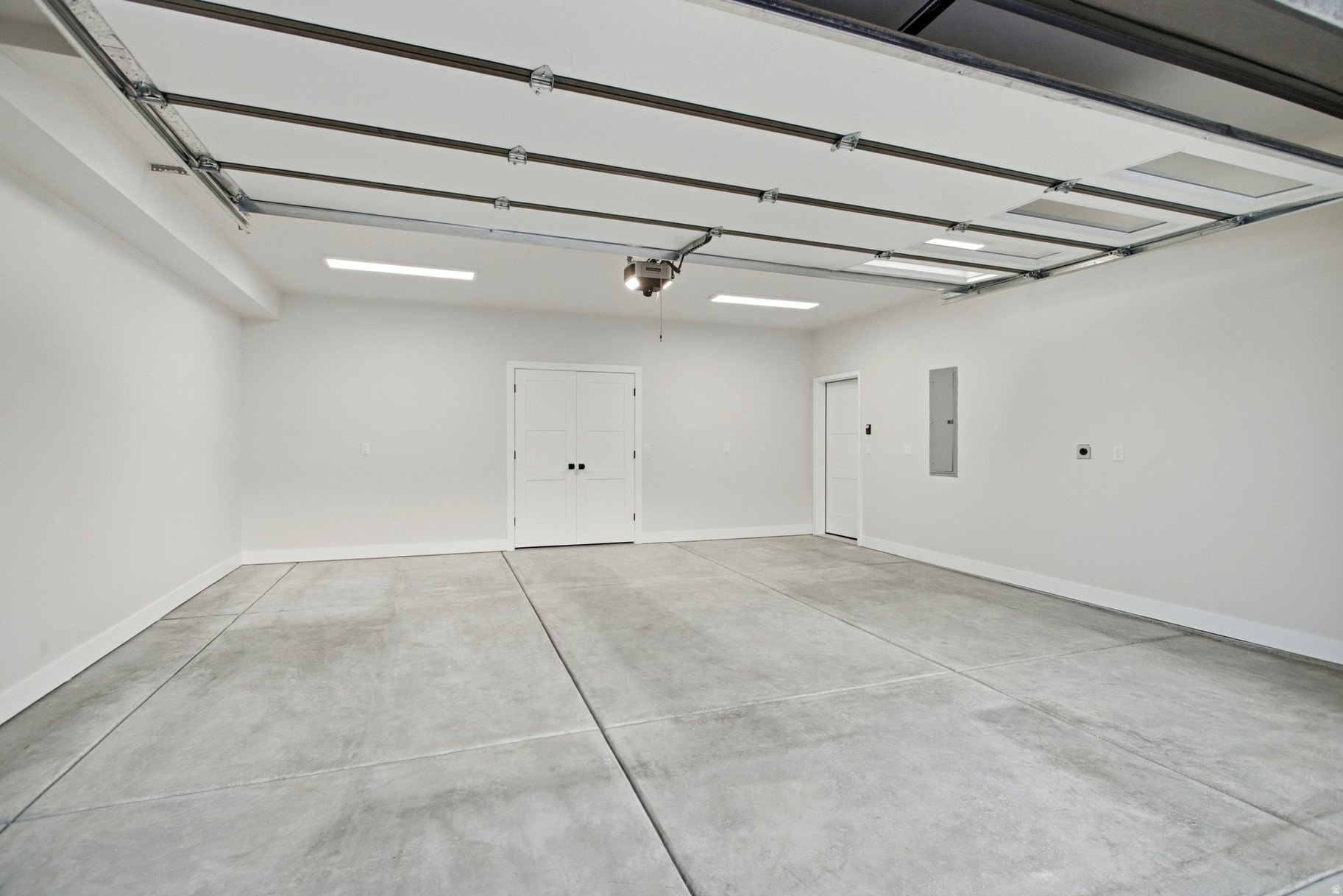 Empty garage with a broad concrete floor and open overhead door.