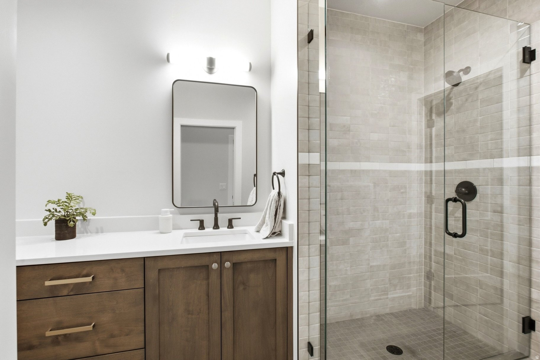 Bathroom with a wood vanity and glass-enclosed tiled walk-in shower.