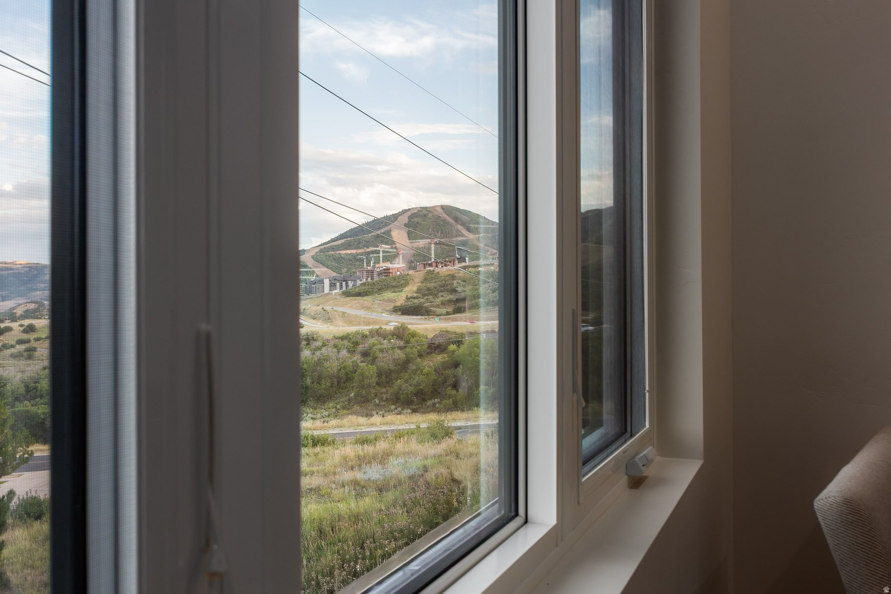Mountain and ski-run view through large interior windows, with resort buildings below.