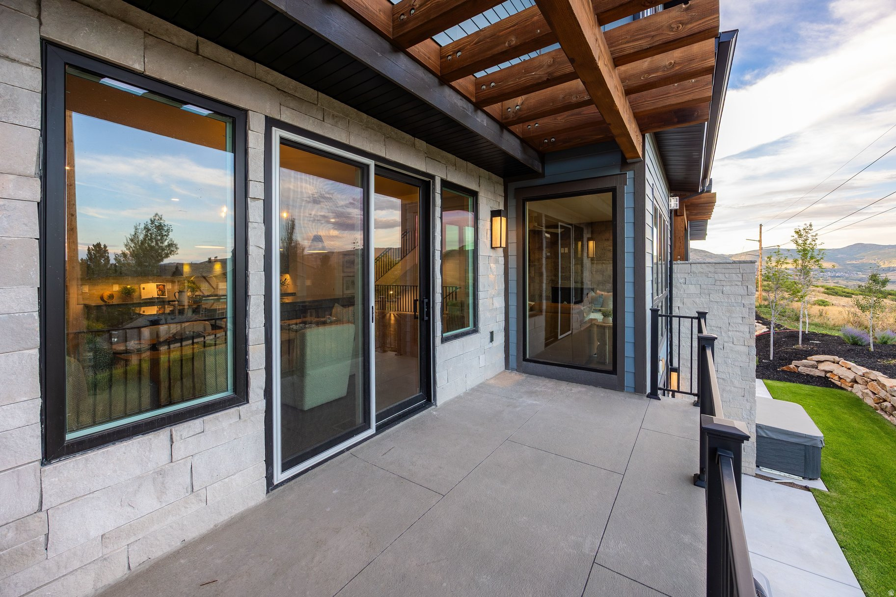 Covered stone-home patio with exposed timber beams and views of the surrounding mountains.