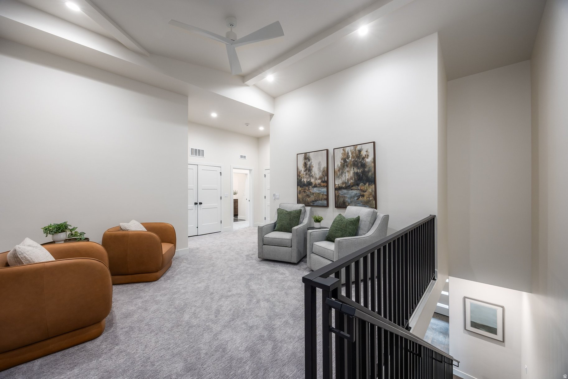 Upstairs sitting area with brown lounge chairs, gray armchairs, and a black stair railing.