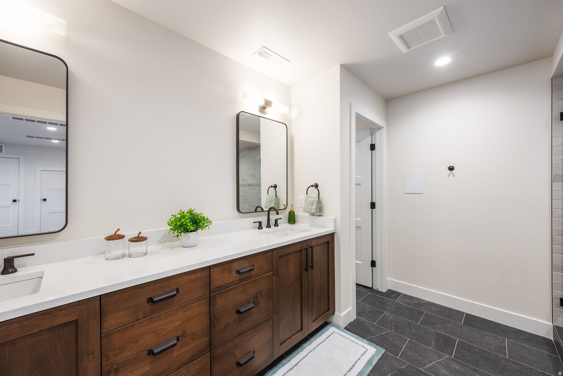 Bathroom with a long double-sink vanity, dark wood cabinets, white countertop, and black-framed mirrors.