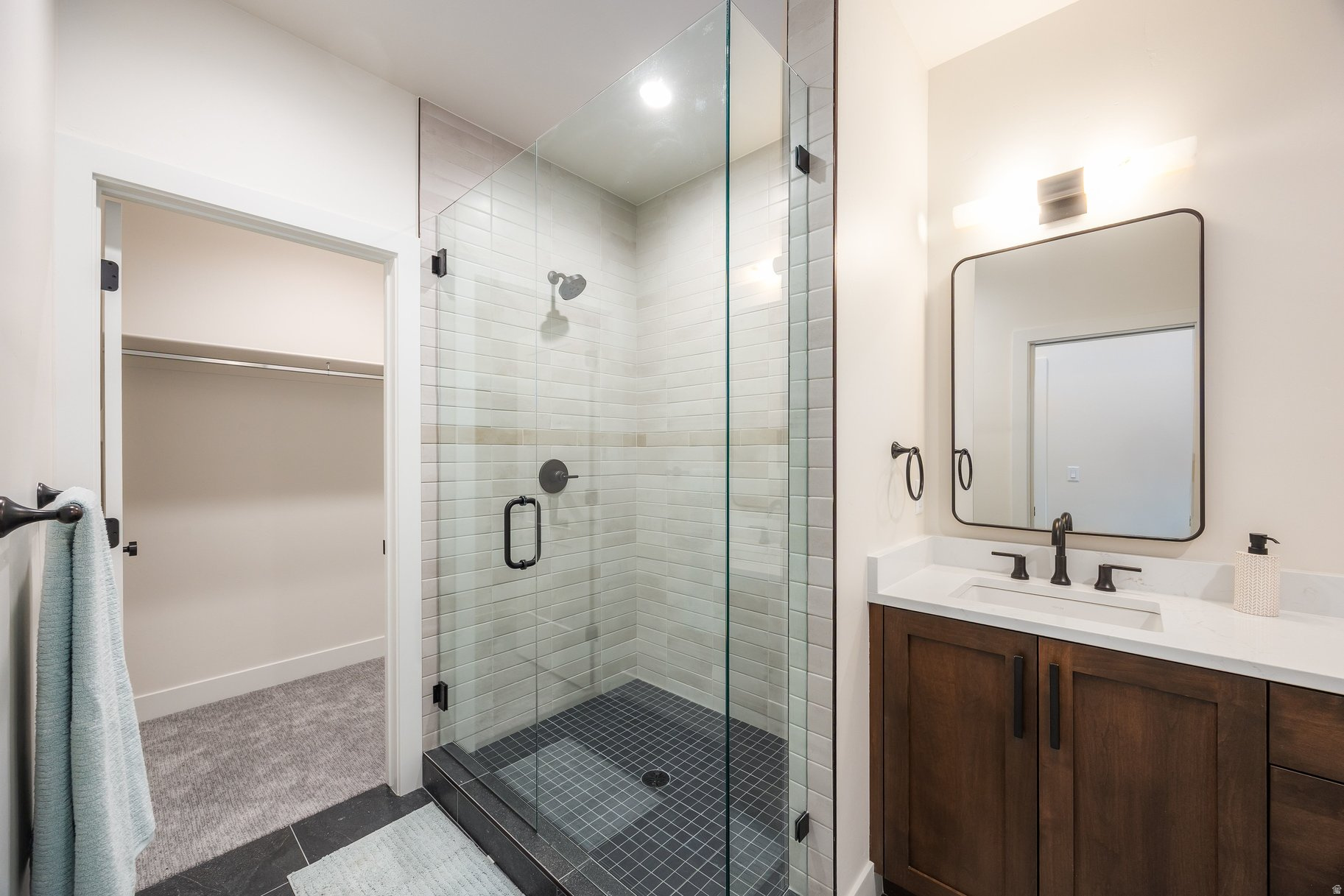 Bathroom with a glass walk-in shower, white tile, and dark wood vanity.