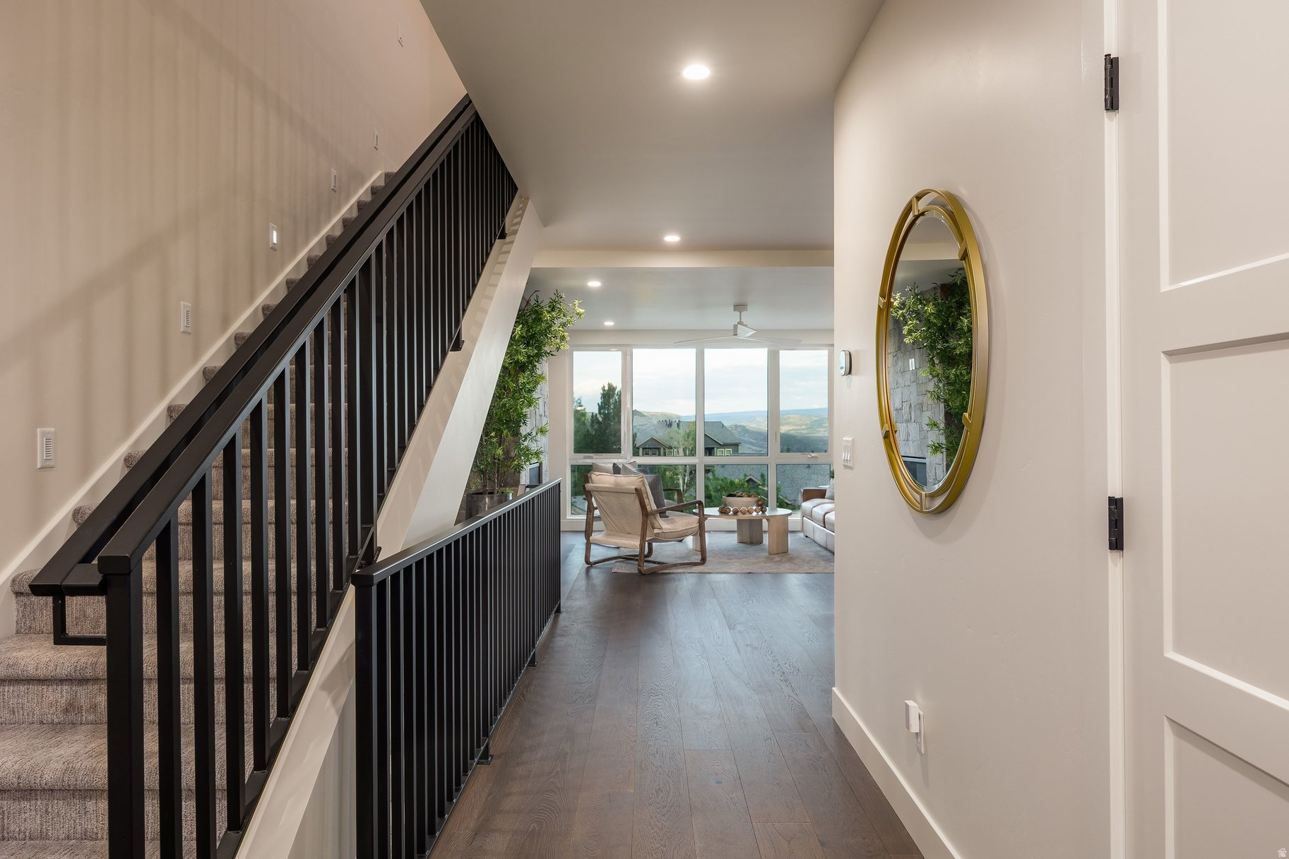 Entry hall with a black-railed staircase leading to a sitting area with mountain views through large windows.