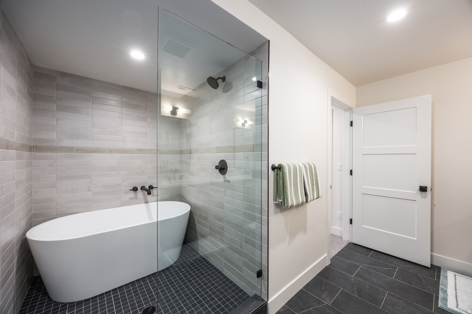 Modern bathroom with a freestanding soaking tub and glass shower with black fixtures.