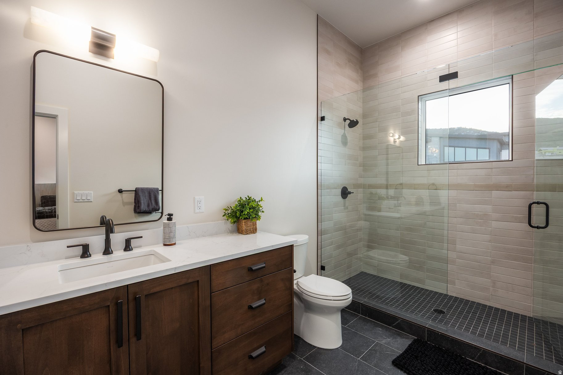 Modern bathroom with a dark wood vanity and glass-enclosed tiled shower.