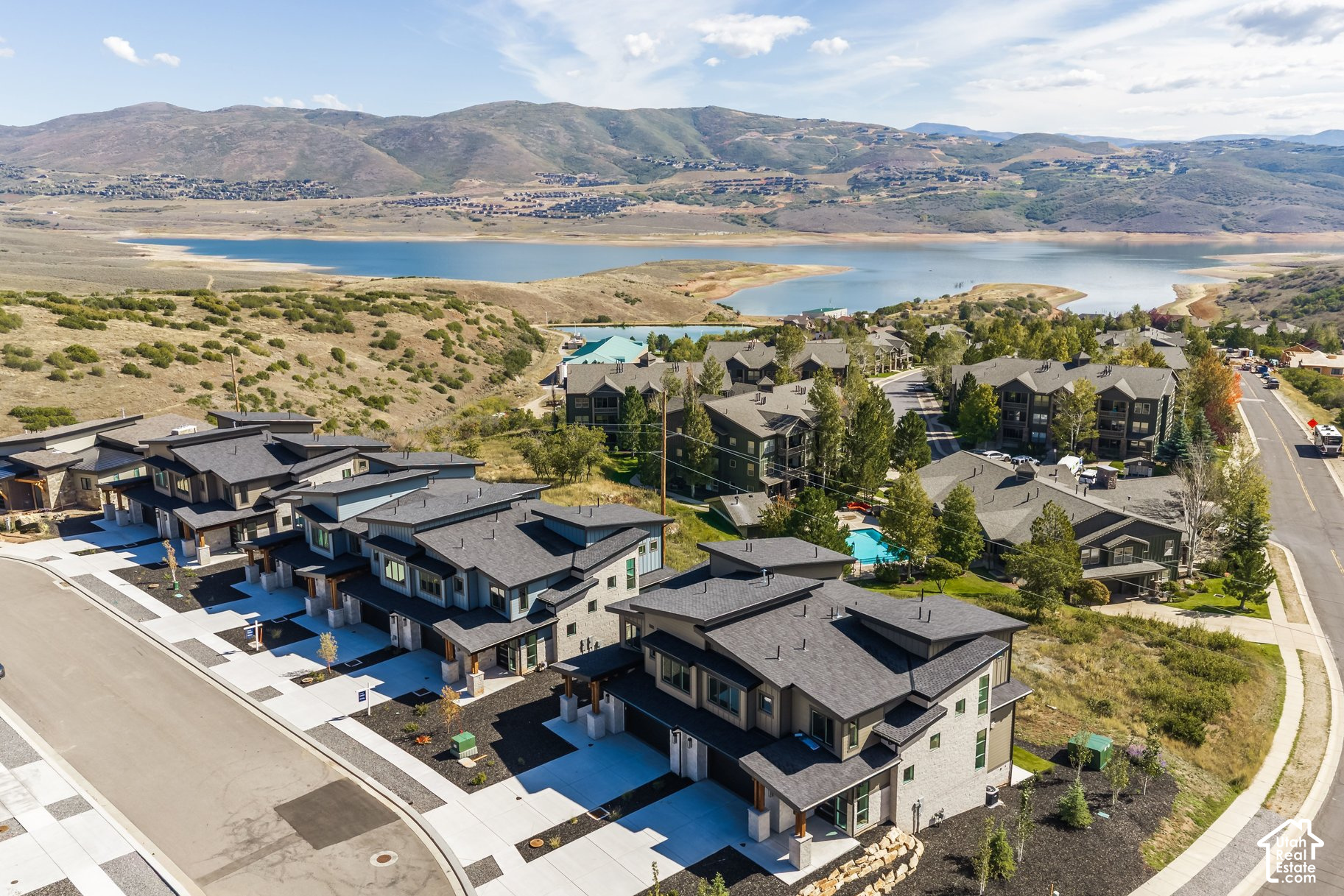 Aerial view of modern homes beside a lake, with mountains in the distance.