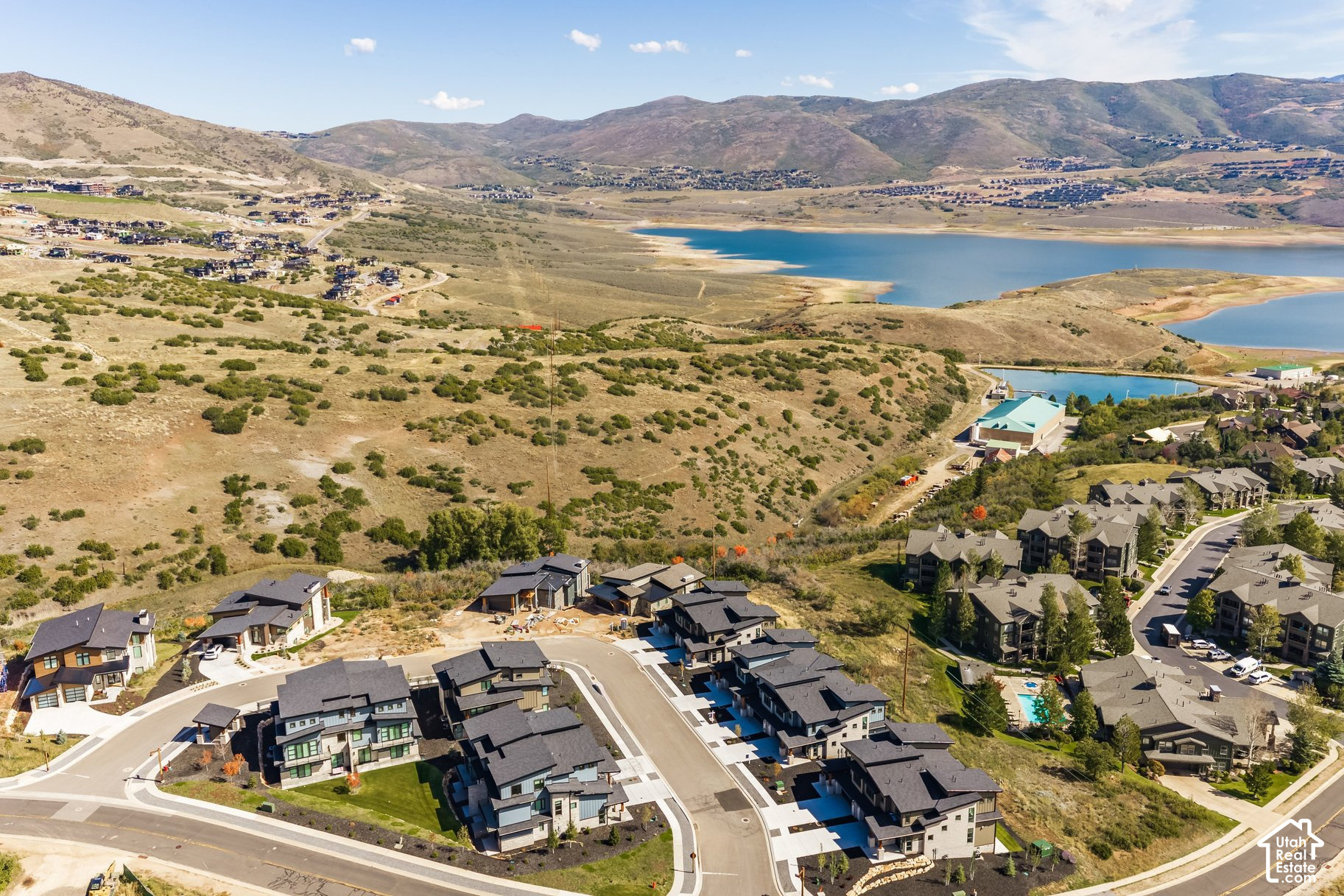 Aerial view of homes beside a reservoir, with rolling hills and mountains in the distance.