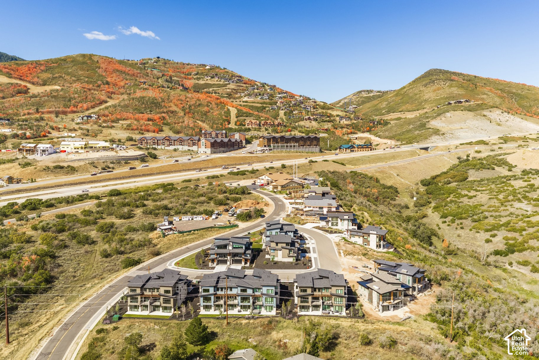 Aerial view of modern homes in a mountain valley, with autumn-colored hills and construction nearby.