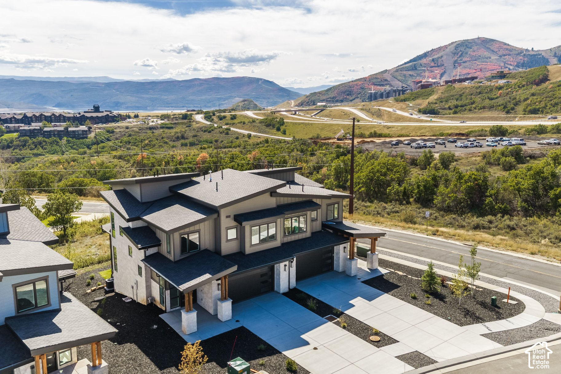 Modern multi-level home with a broad driveway and autumn-colored mountains in the distance.