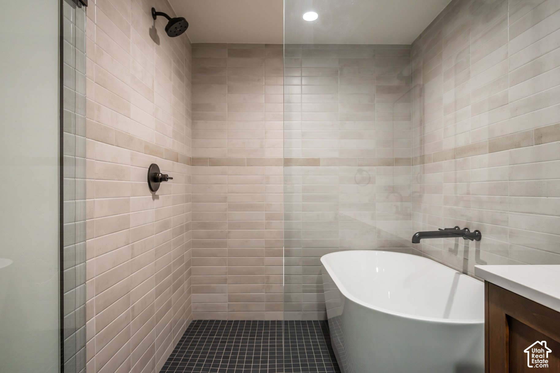 Modern bathroom with a glass-enclosed tiled shower and white freestanding bathtub.