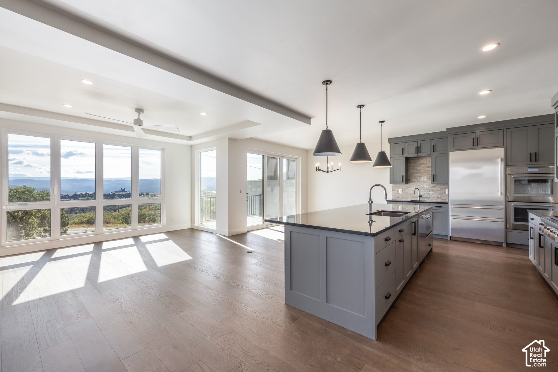 Open kitchen with gray cabinets and a large island, brightened by windows overlooking distant mountains.