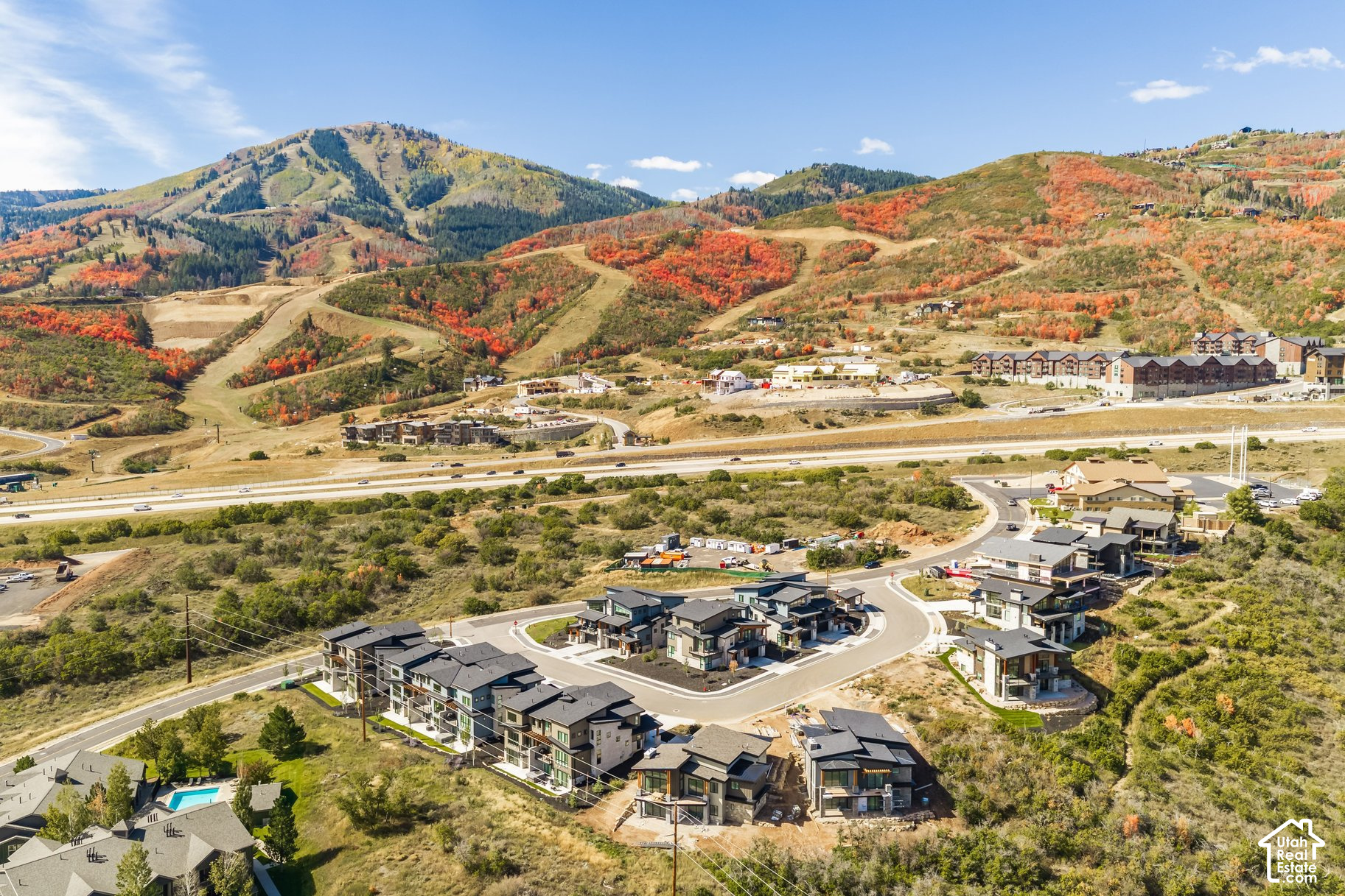 Aerial view of a mountain neighborhood with modern homes and autumn-colored slopes.