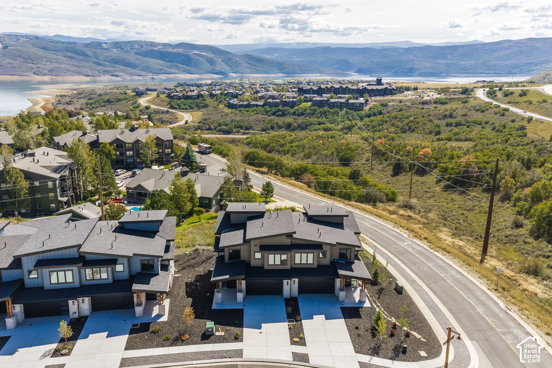 Aerial view of modern homes overlooking a lake and mountain ranges.