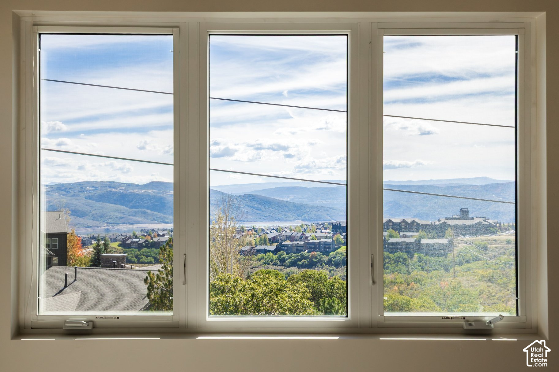 Mountain and water views over a neighborhood, seen through three large windows.