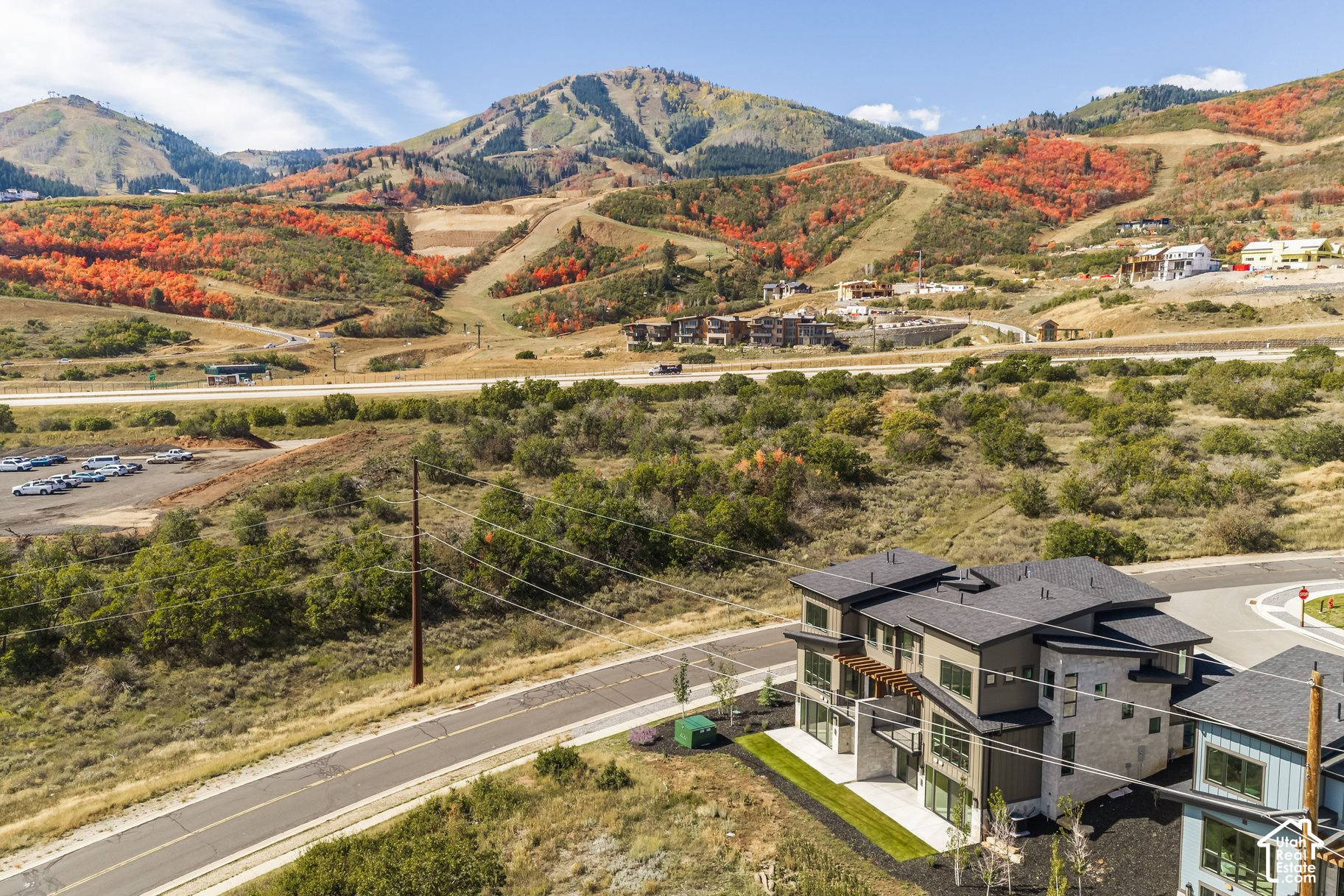 Modern home below autumn-colored mountain slopes, viewed from above.