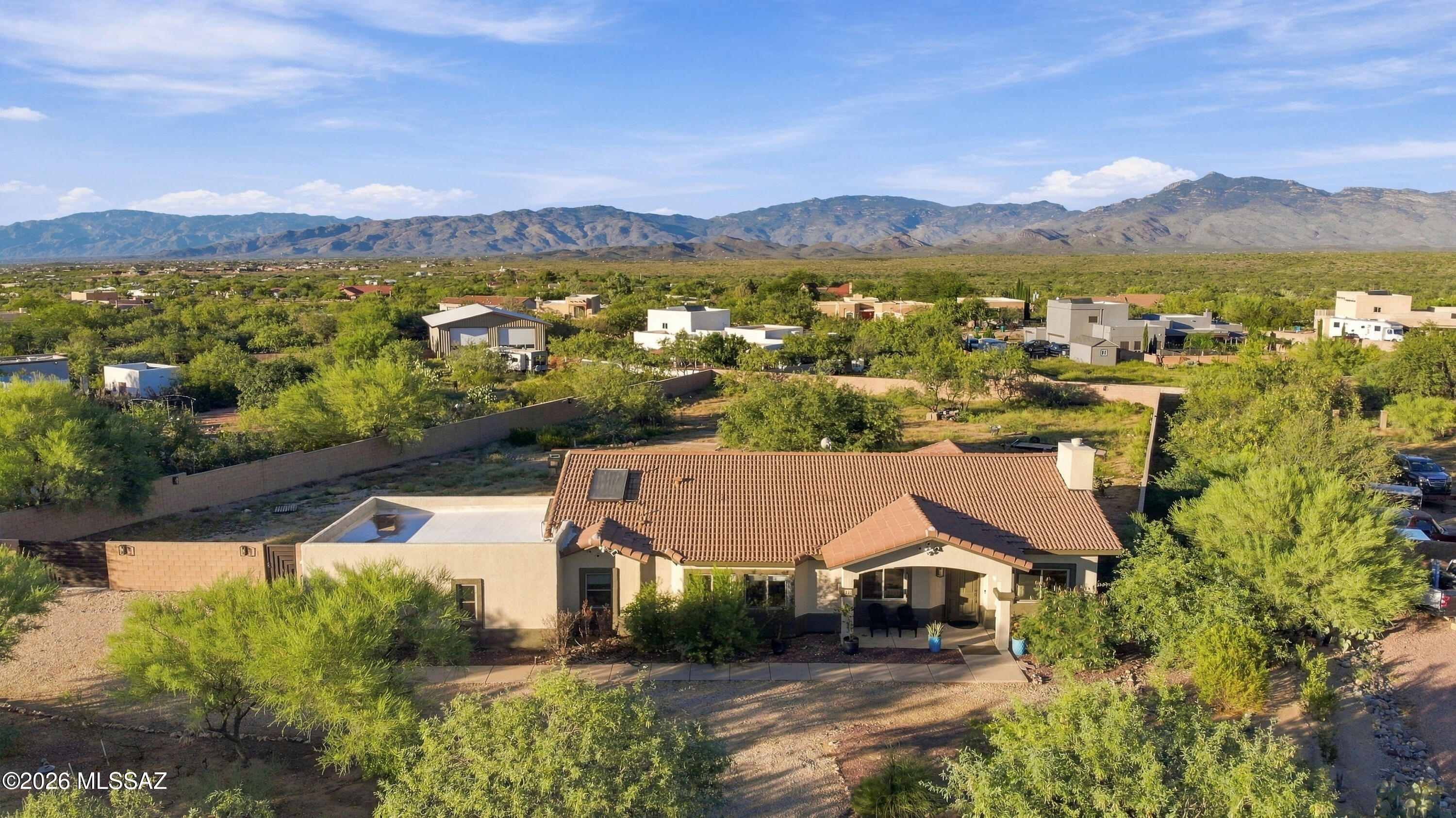 Aerial view of a tile-roofed home with desert landscaping and mountains in the background.