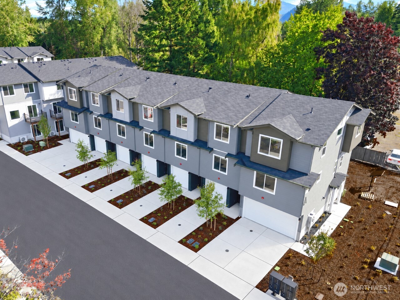 Aerial view of modern gray townhomes with attached garages and landscaped front walks.